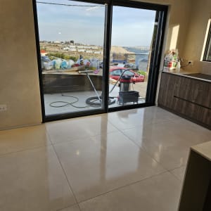 רצפה נקייה עם שואב אבק וחומרי ניקוי ליד חלון גדול