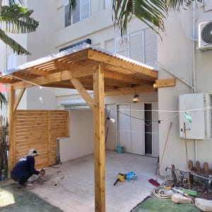 פרגולה מעץ עם גג פלסטיק בחצר הבית