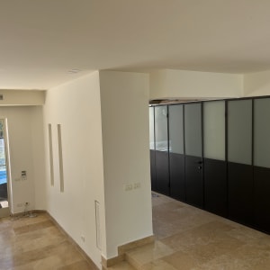 קירות צבועים בלבן בחדר פנימי עם דלתות זכוכית כהות