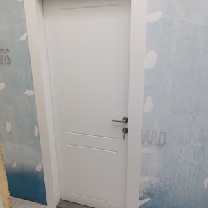 דלת לבנה עם ידית כסופה על רקע קיר כחול