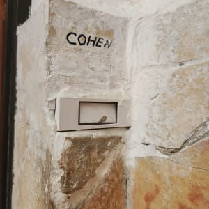 פעמון דלת על קיר אבן עם שם כהן