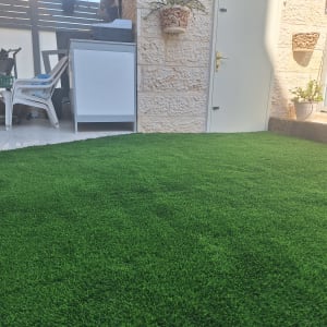 דשא סינתטי ירוק עם עציצים על הקיר