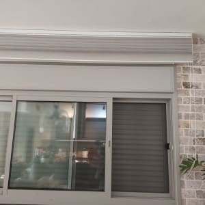 תריסים וחלון זכוכית על קיר לבנים
