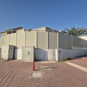 גדר אלומיניום הייטק בגוון שמנת המותקנת מעל חומה היקפית