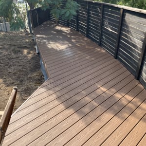 דק עץ חום עם מעקה שחור בגן