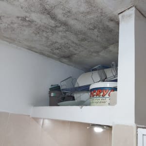 תקרה עם כתמי רטיבות ודלי צבע על מדף