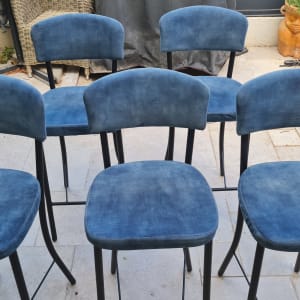 שישה כיסאות כחולים על מרפסת עם צמחים