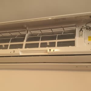 מזגן מותקן על קיר עם מכסה פתוח