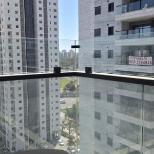מרפסת עם מעקה זכוכית ונוף לבניינים