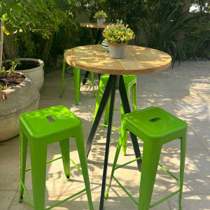 שולחן עגול עם כיסאות ירוקים ועציץ קטן