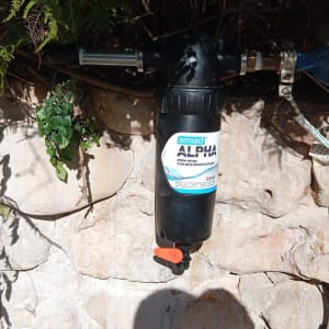 מסנן מים שחור עם ברז כתום על קיר אבן