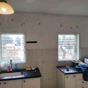 מטבח עם כיור, חלונות, ומוצרי ניקוי על השיש