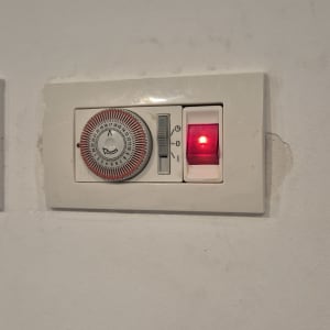 מתג טיימר חשמלי לדוד עם נורית חיווי דולקת מותקן על הקיר