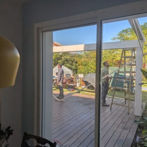 שני אנשים עובדים על פרגולה מעץ בגינה