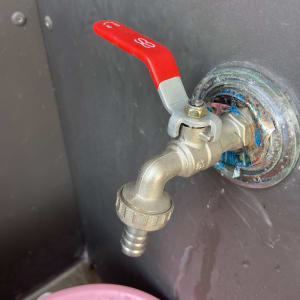 ברז מתכת עם ידית אדומה ודלי ורוד