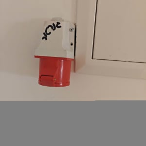 שקע חשמלי אדום מותקן על קיר לבן