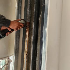 ידיים מחזיקות כלי עבודה ליד צינורות חלודים