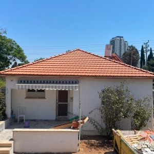 בית עם גג רעפים אדום ועבודות בנייה בחצר