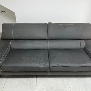 ספה אפורה עם תפרים לבנים על רצפת אריחים אפורה