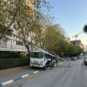 משאית מנוף חונה ברחוב ליד בניין ועצים