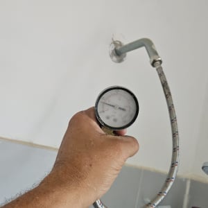 יד מחזיקה מד לחץ ליד צינור מקלחת