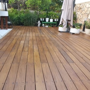 דק עץ עם עציצים ופרגולה בגינה