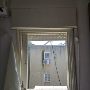 חלון פתוח עם תריסים, מבט על בניין ממול