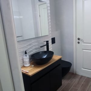 כיור שחור על משטח עץ בחדר אמבטיה משופץ