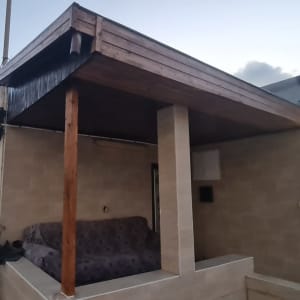 פרגולה מעץ עם עמודי תמיכה וספה מכוסה