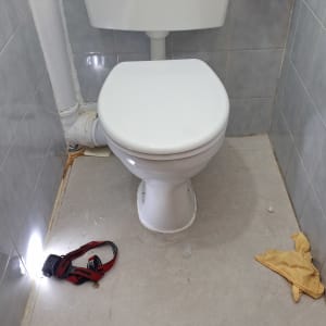 אסלה עם צינור מים וכלים על הרצפה