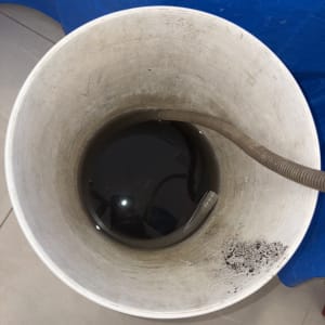 דלי עם צינור ומים כהים על רצפה