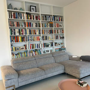 ספה אפורה מול מדפי ספרים מלאים