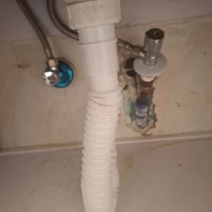 צינור פלסטיק לבן מתחת לכיור עם חיבורים