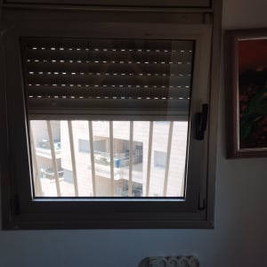 תריסים סגורים למחצה על חלון עם סורגים