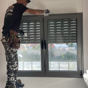 אדם על סולם מתקין תריסים בחלון