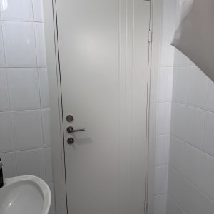 דלת לבנה עם ידית מתכת בחדר אמבטיה