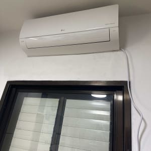 מזגן מותקן על קיר מעל חלון עם תריסים