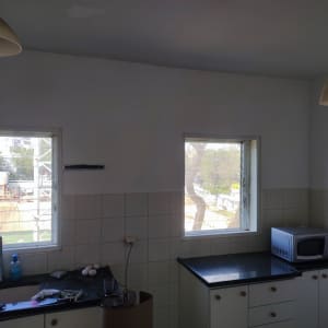 מטבח עם קירות צבועים, חלונות פתוחים ומיקרוגל על השיש