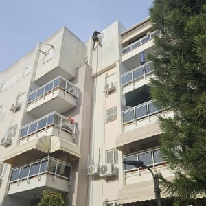 אדם צובע קיר חיצוני של בניין גבוה