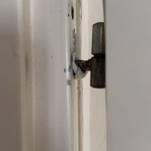 ציר דלת מתכת מותקן במסגרת דלת לבנה