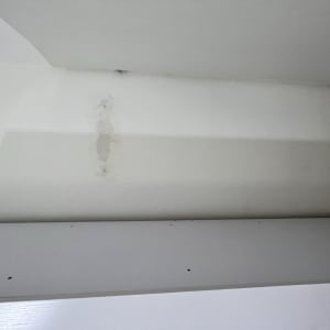 קיר עם סימני רטיבות מעל מדף לבן