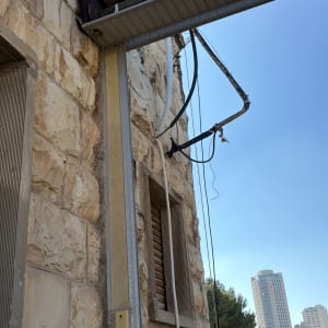 אדם על גג ליד קיר אבן עם צינורות