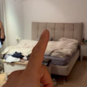חדר שינה עם מיטה ואצבע המצביעה במרכז התמונה