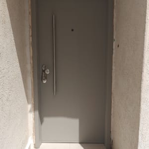 דלת אפורה עם ידית מתכת בקיר חיצוני