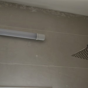 מקלחת עם ראש מקלחת מרובע וקיר אריחים