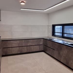 מטבח חדש עם ארונות אפורים ומשטח עבודה שחור
