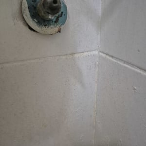 ברז ישן עם סימני חלודה על קיר אריחים