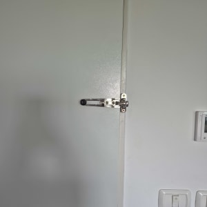 מנעול דלת עם בריח מתכת על דלת לבנה