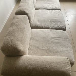 ספה בהירה עם שלושה מושבים, ללא כתמים נראים לעין.