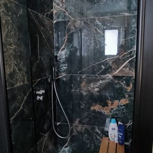 מקלחון עם קירות שיש, ראש מקלחת ומדף עץ